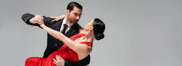 Mann im Anzug führt Tango mit elegantem Partner isoliert auf grauem Banner vor — Stockfoto