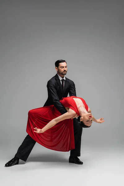 Toute la longueur d'élégant couple dansant tango sur fond gris — Photo de stock