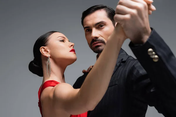 Professional ballroom dancers holding hands isolated on grey — Stock Photo