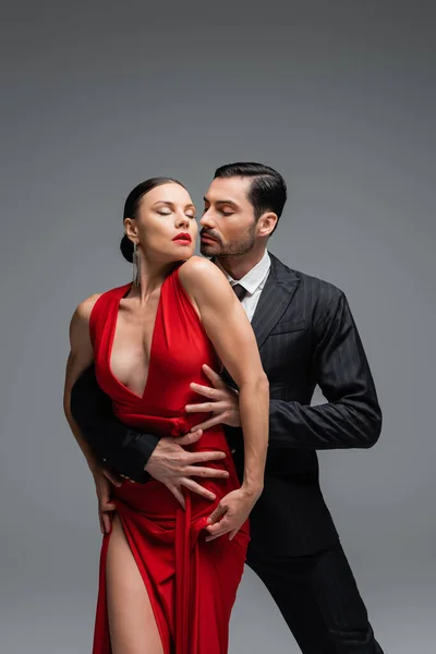 Uomo in giacca e cravatta toccare partner mentre danza tango isolato su grigio — Foto stock