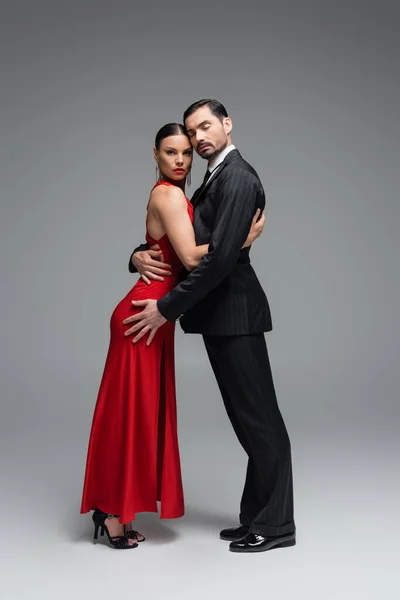 Professional dancers hugging while dancing on grey background — Stock Photo