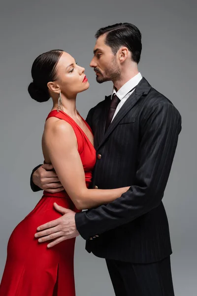 Vue latérale de danseurs de salon s'embrassant et se regardant isolés sur le gris — Photo de stock