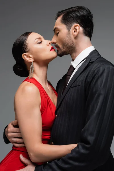 Seitenansicht eines eleganten Paares, das sich isoliert auf Grau küsst — Stockfoto