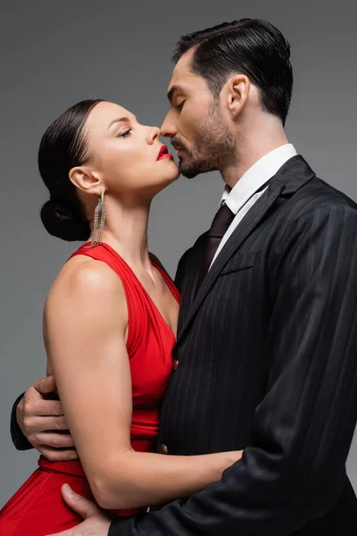 Vue latérale du couple élégant embrassant isolé sur gris — Photo de stock