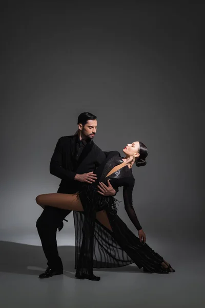 Elegant couple dancing tango on grey background with shadow — Stock Photo