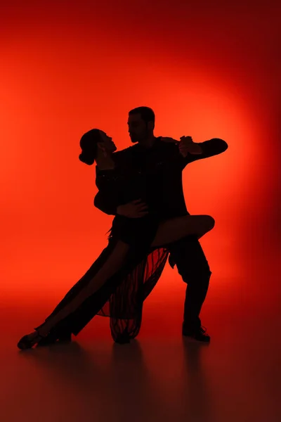 Silhouette of couple dancing tango on red background — Stock Photo