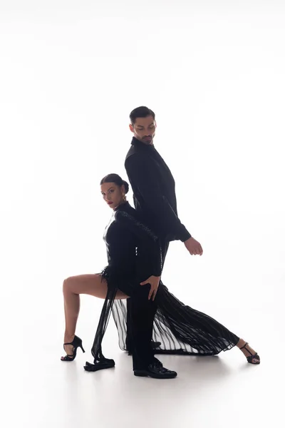 Elegante donna in abito nero che esegue tango con partner su sfondo bianco — Foto stock