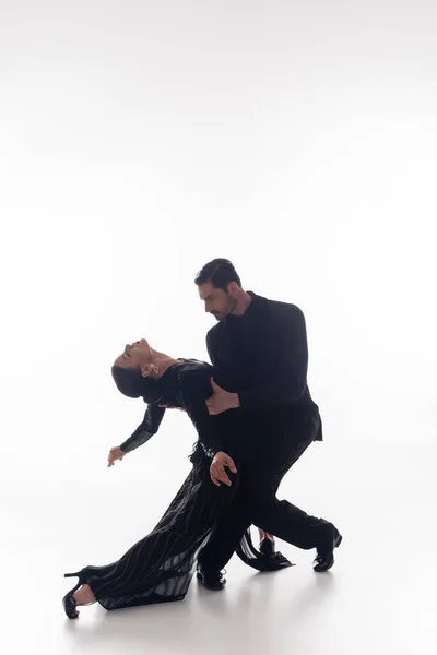 Couple in suit and dress performing tango on white background — Stock Photo