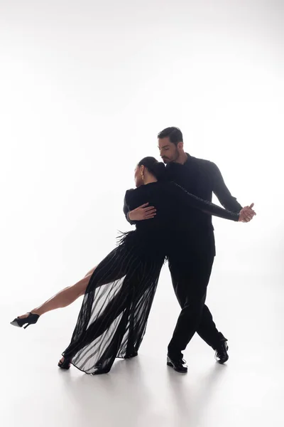 Homem de terno realizando tango com mulher elegante no fundo branco — Fotografia de Stock
