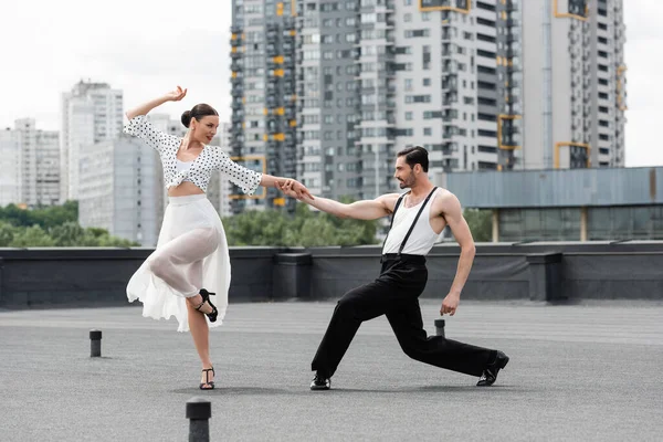 Vista laterale di ballerini sorridenti che si muovono sul tetto dell'edificio all'aperto — Foto stock