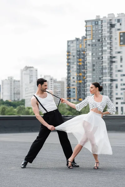 Vista lateral de bailarina con estilo en tacones bailando con pareja en el techo - foto de stock