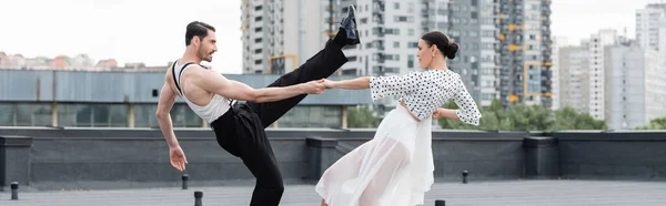 Vista laterale di ballerini alla moda che eseguono coreografie sul tetto durante il giorno, banner — Foto stock