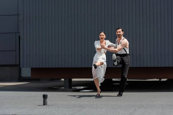 Bailarines positivos mirando hacia otro lado mientras realizan coreografías en la azotea - foto de stock