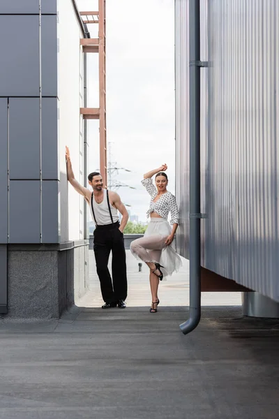 Danseuse de salon souriante debout près du partenaire sur le toit du bâtiment à l'extérieur — Photo de stock