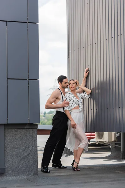 Ballerina che abbraccia sorridente partner in tacchi e gonna sul tetto dell'edificio durante il giorno — Foto stock