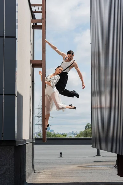 Professionelle Tänzer posieren tagsüber auf Leiter auf Hausdach — Stockfoto