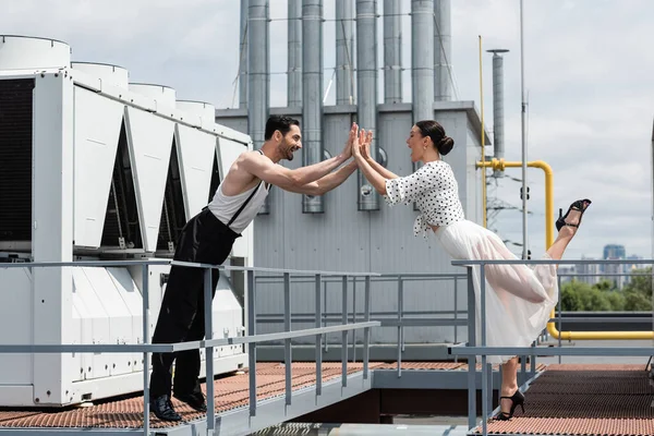 Vista lateral de bailarines profesionales emocionados dando cinco en la azotea del edificio - foto de stock