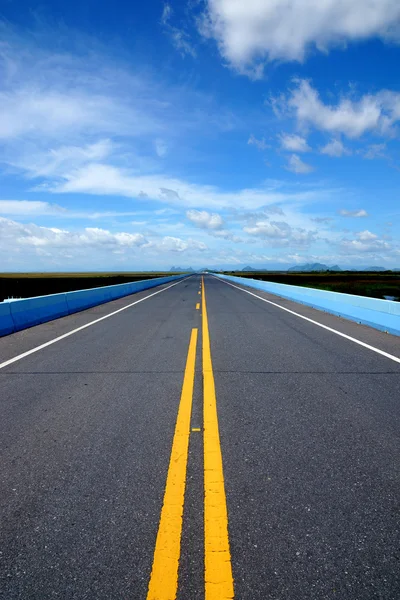 Blauer Himmel mit Könnern, leere Straße und Verkehrslinien. — Stockfoto