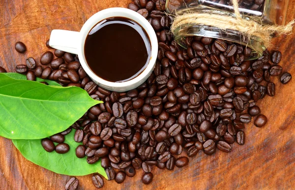 Смажені кавові зерна на дереві та чорній каві . — стокове фото