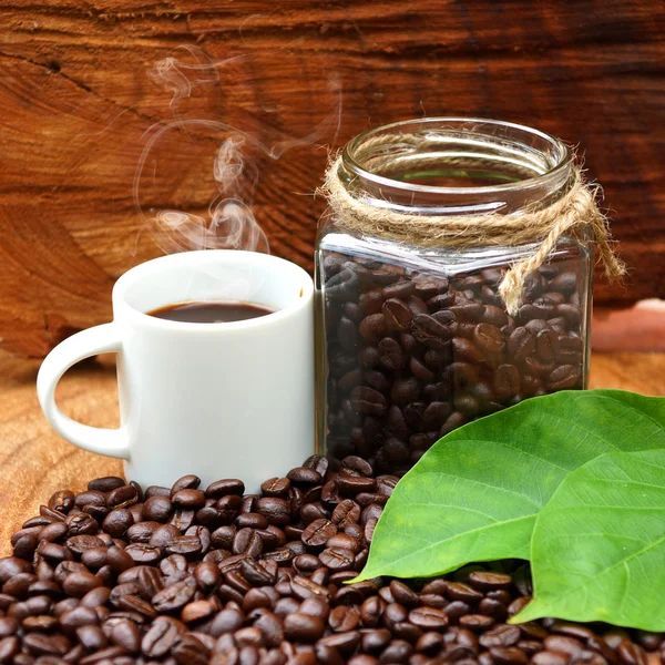 Granos de café asados en madera y café negro . — Foto de Stock