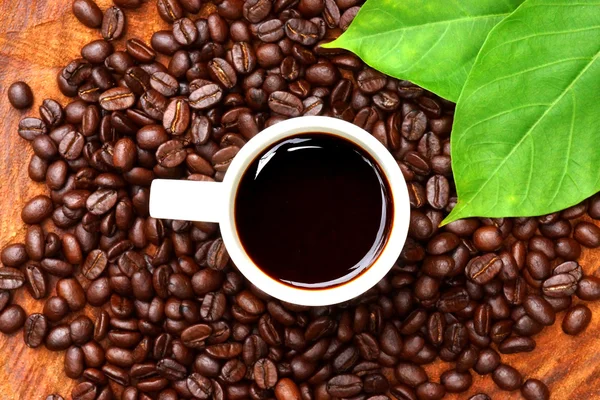 Pražená kávová zrna na dřevo a černá káva. — Stock fotografie
