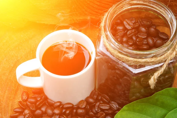 Rostade kaffebönor på trä och svart kaffe på morgonen. — Stockfoto
