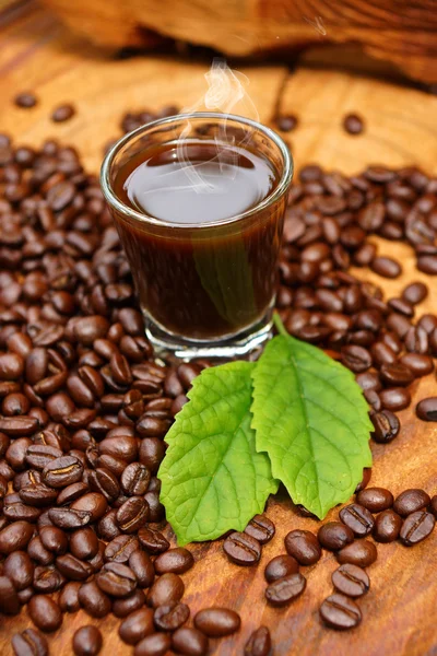 Gebrande koffiebonen op hout en zwarte koffie. — Stockfoto