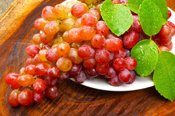 Свежий красный виноград на коричневом дереве . — стоковое фото