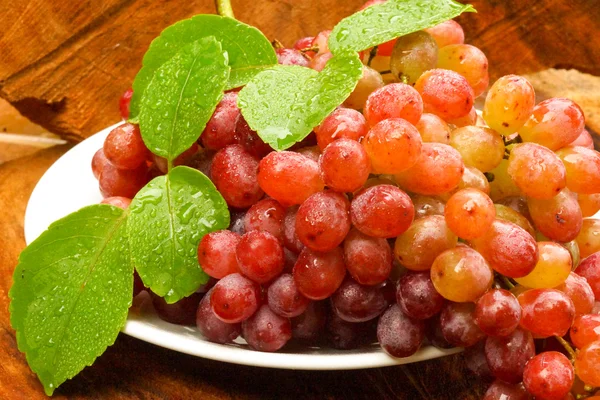 Uvas vermelhas frescas em madeira castanha . — Fotografia de Stock