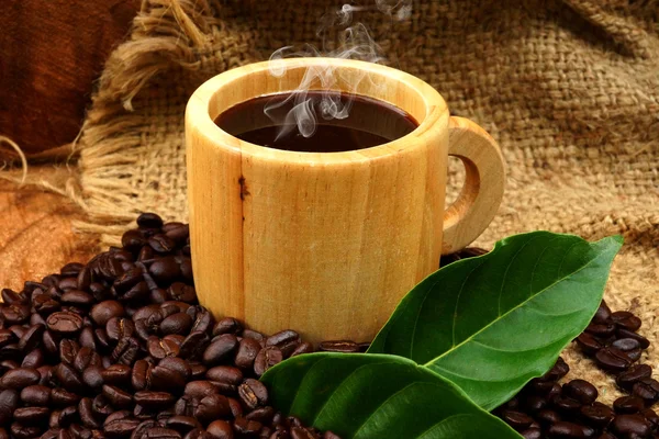 Granos de café tostados en madera y negro café en un vaso de madera. — Φωτογραφία Αρχείου