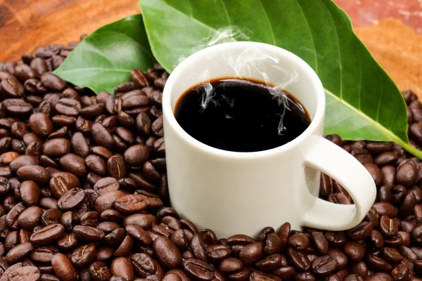 Kaffe och kaffebönor på trä bakgrund — Stockfoto