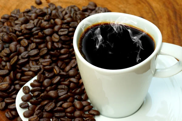 Kaffeetasse und Bohnen auf Holz-Hintergrund. — Stockfoto