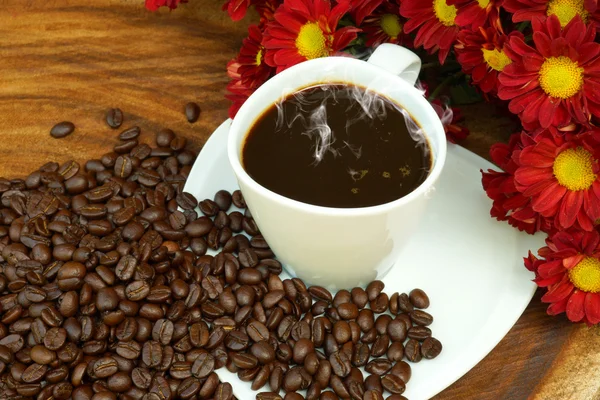 Tasse à café et haricots sur fond de bois . — Photo