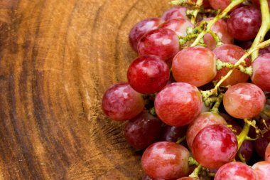 kahverengi ahşap üzerine taze kırmızı üzüm.