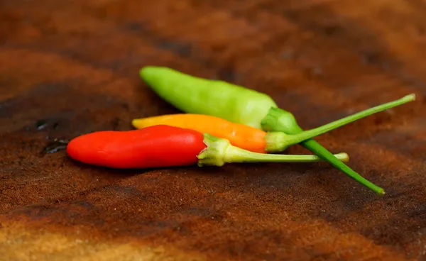 Pimientos verdes y rojos frescos y picantes en pisos de madera . — Foto de Stock