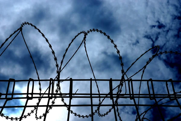 Barbed wire on dark fence. silhouette photo — Stock Photo, Image