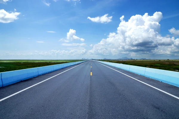 Blauwe lucht met kan lege weg en het verkeer lijnen. — Stockfoto