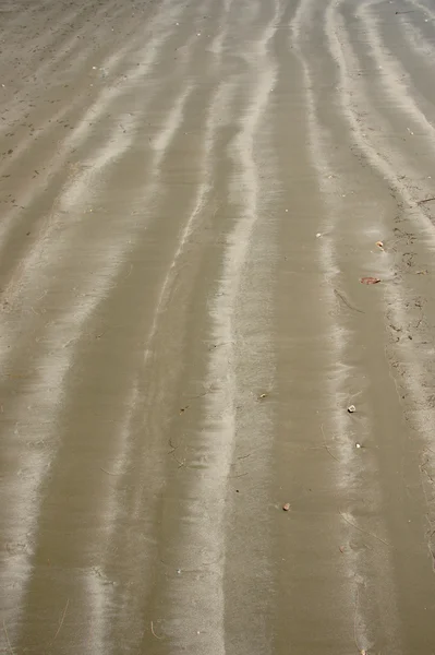 Wellenmuster pusten Sand auf den Strand. — Stockfoto