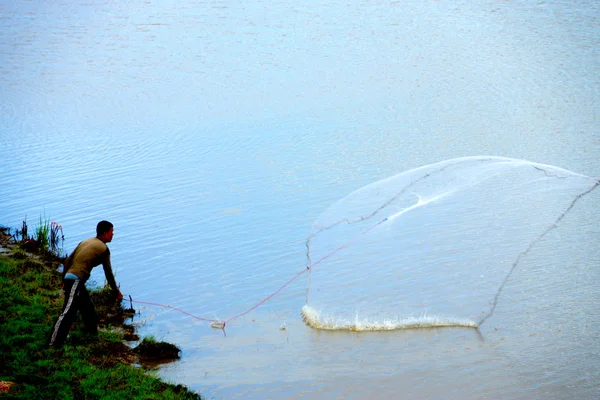 Ein Mann wirft Fischernetze in den See. Thailand. — Stockfoto