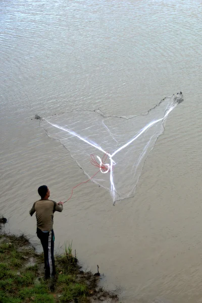 Un uomo che lancia la rete da pesca nel lago. Tailandia . — Foto Stock