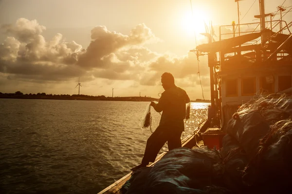 Siluetas pescador casting en un barco de cangrejo . — Foto de Stock