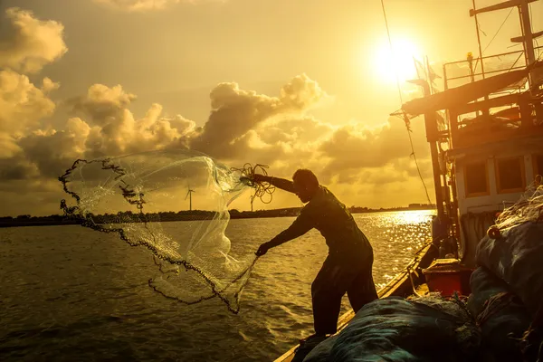 Silhuetter fisherman gjutning på en krabba båt. — Stockfoto