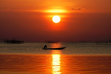 gün batımında göl ve balıkçı tekneleri.
