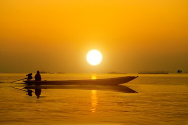 siluetleri balıkçı ve göl günbatımı.
