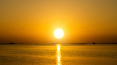 günbatımı gökyüzü ve göl üzerinde büyük güneş.