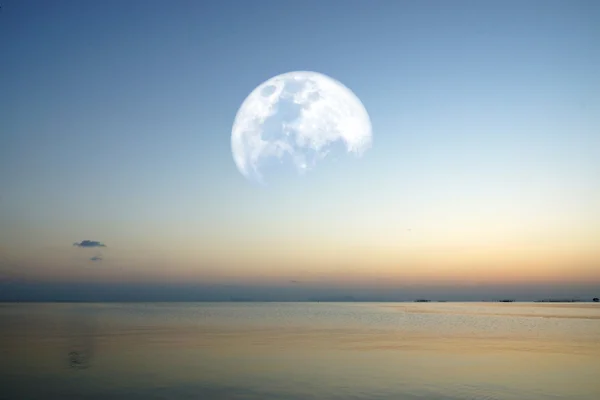 Maan op meer met blauwe hemel en kleurrijke zonsondergang — Stockfoto