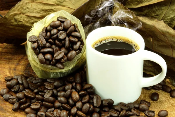 Kaffee und geröstete Kaffeebohnen auf Holz — Stockfoto