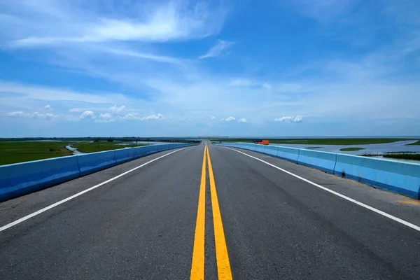 Estrada vazia e as linhas de trânsito amarelas com céu azul . — Fotografia de Stock
