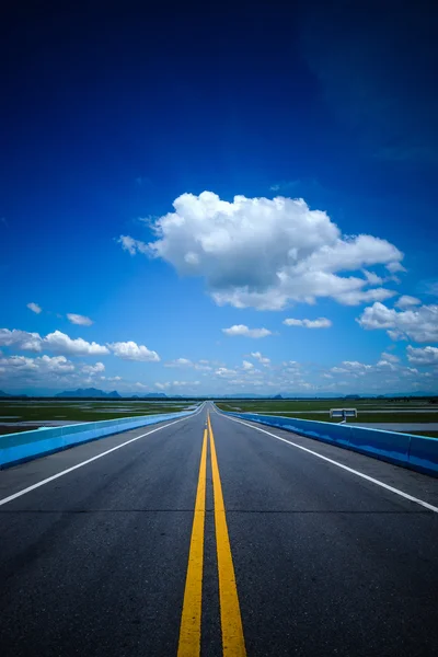 Tom väg och gula trafikerar linjer med blå himmel. — Stockfoto