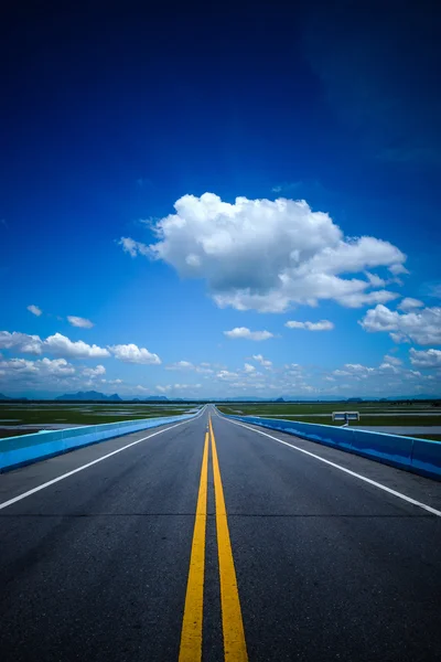 Leere Straße und die gelben Verkehrslinien mit blauem Himmel. — Stockfoto